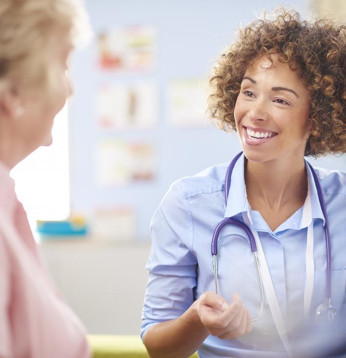 Caregiver talking with elderly woman in a waiting room